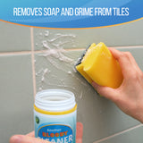A hand holds a yellow sponge against a tiled wall while applying a cleaning paste from a small white jar labeled 'Another Bloody Cleaner.' Text at the top reads 'Removes Soap and Grime from Tiles.