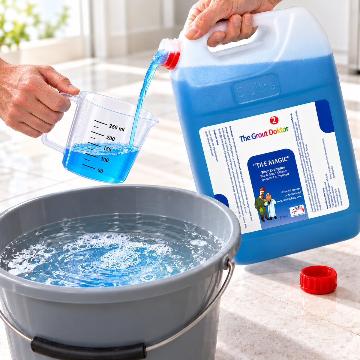 A person pours bright blue liquid from a large blue plastic jug labeled 'The Grout Doctors Tile Magic" into a clear measuring cup, with a gray bucket of water in the foreground and the red cap on the floor nearby.